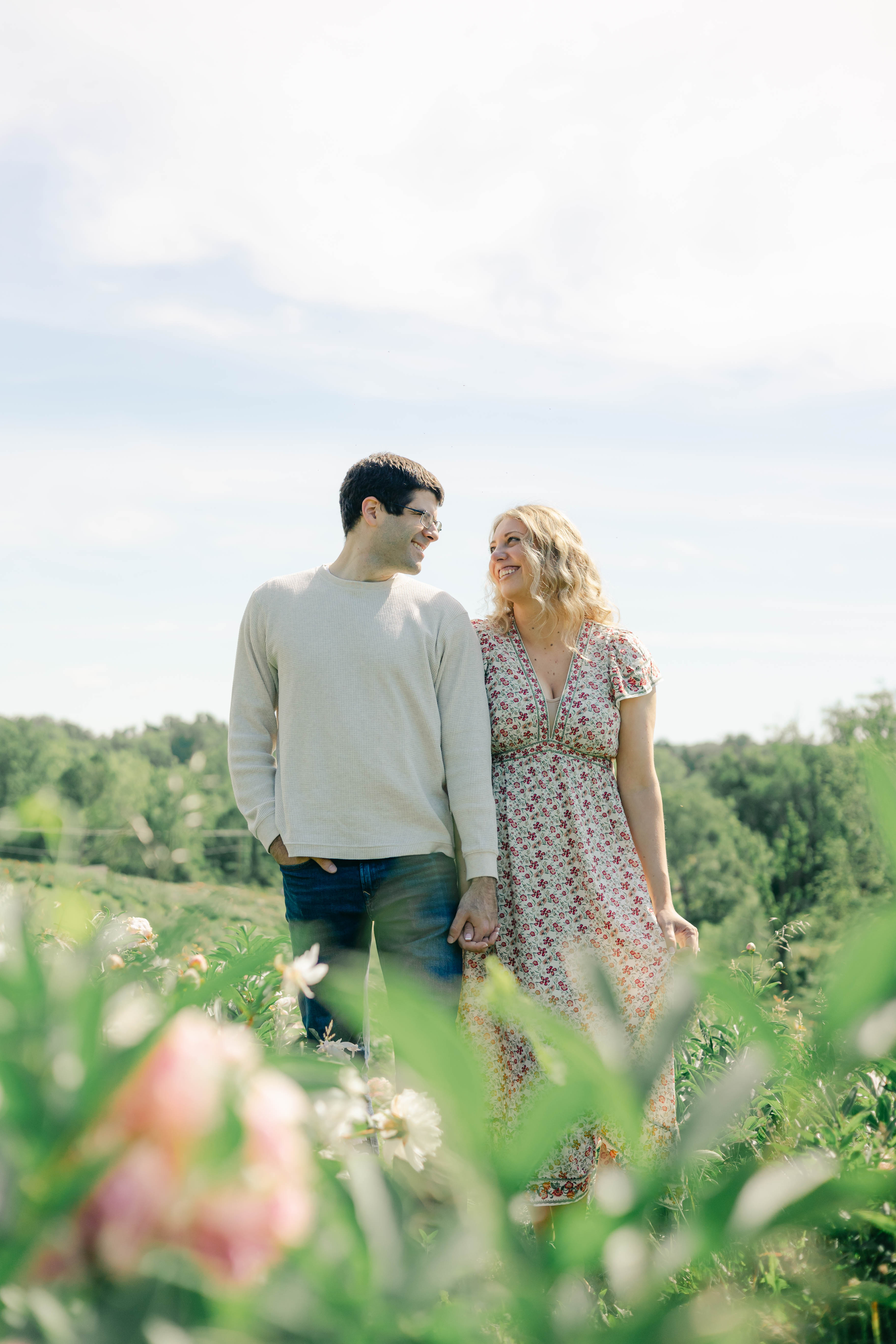 Couple holding hands among blooming wildflowers on a summer hilltop